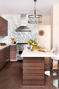 The oversize glass tiles on the backsplash are backed in silver leaf to brighten the already light and fun cooking space. Silver pendants give it party vibes